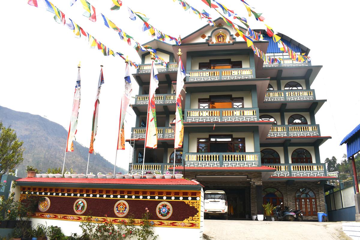 Hotel Pema Lhatse building with Himalayan mountains in background, prayer flags, Dirang