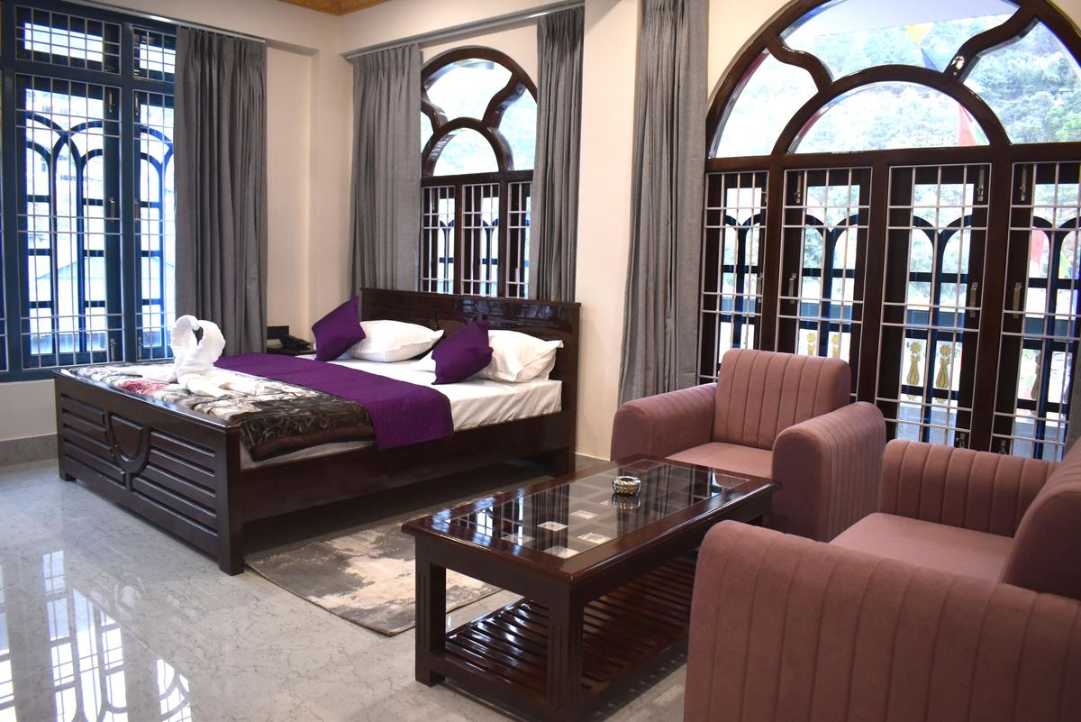 Deluxe Double Room at Hotel Pema Lhatse Dirang with king bed, sofa set and large arched windows, Rs 5000 per night