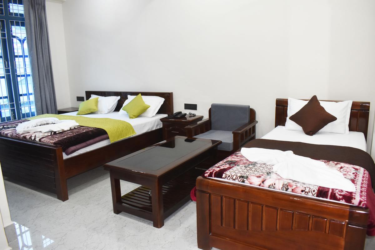 Family Room at Hotel Pema Lhatse Dirang with twin beds, wooden chairs and sitting area, Rs 4000 per night